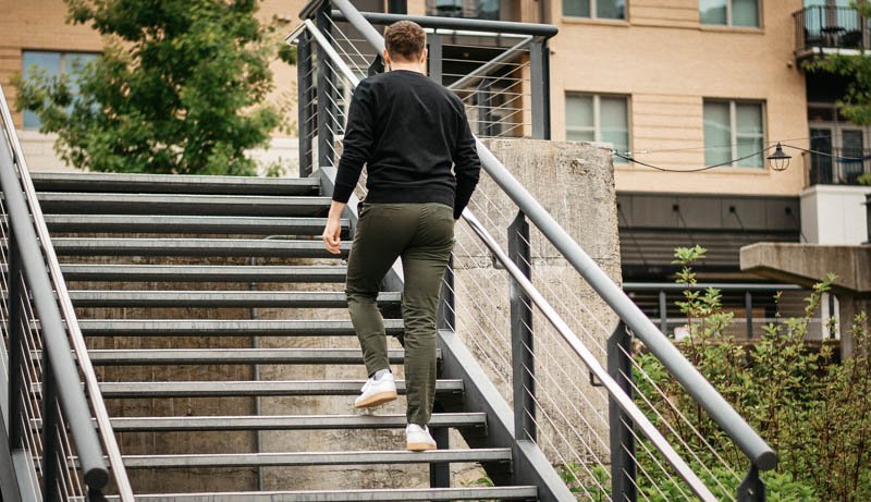 model walking up steel steps with olive asket chinos