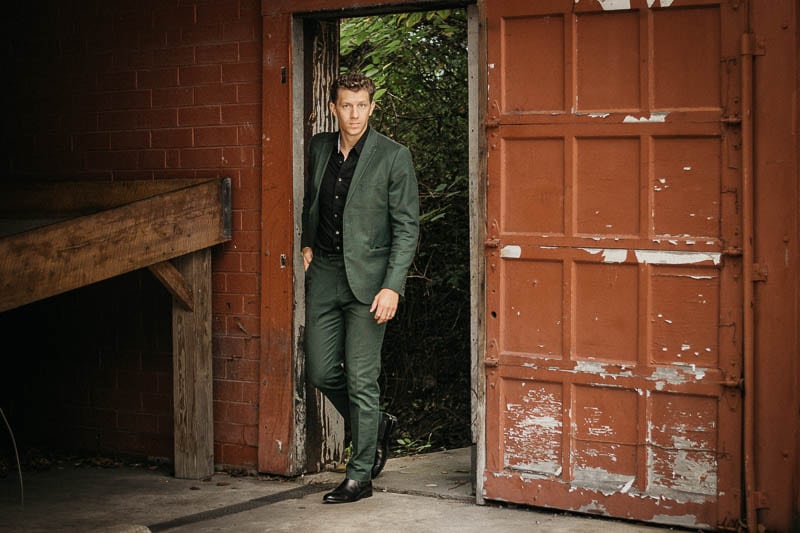 model walking with green suit and black shirt and ace marks black chelsea boots