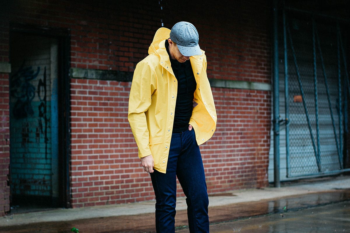 model wearing a yellow rains waterproof jacket and raw denim jeans