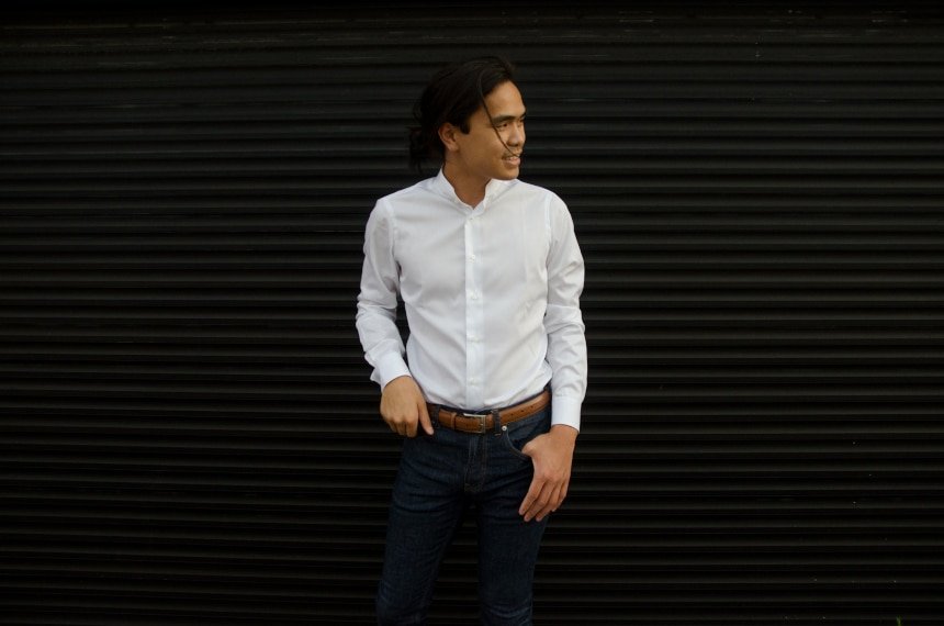 Model Wearing Apposta Coolmax Twill and Leaning Against a Black Garage Door And Smiling Straight On