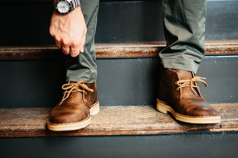 Model wearing jack mason watch and clarks desert boot adjusting pant cuff