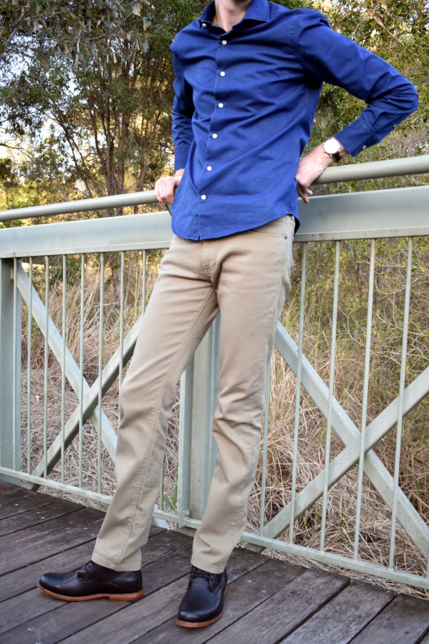 Model Wearing Mott and Bow Slim Mercer in Olive with Slim Semi Spread Wythe in Dark Blue and holding onto bridge railing