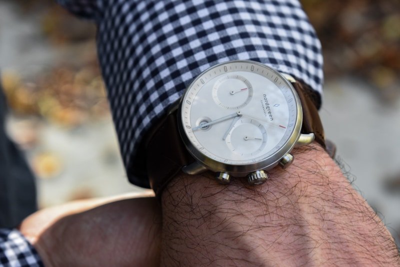 model wearing nordgreen pioneer white dial against blue checkered shirt