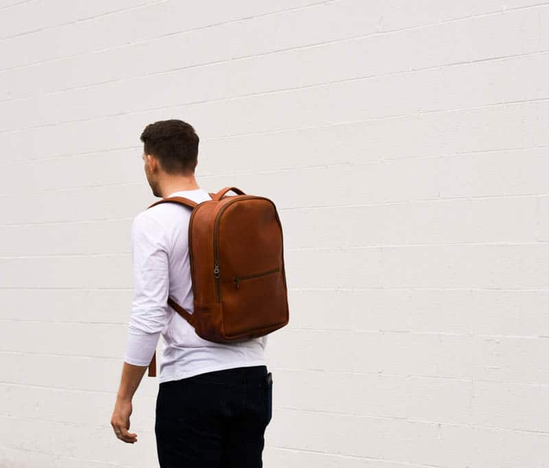 model wearing parker clay atlas leather backpack against white wall