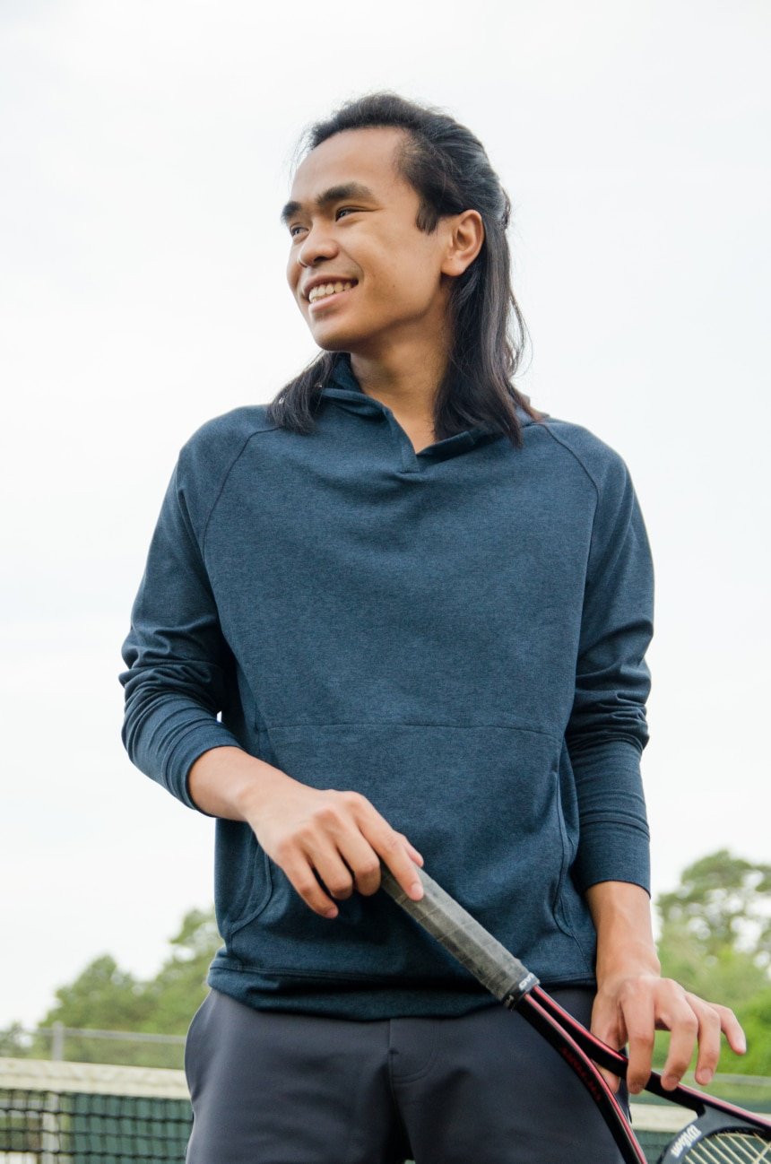 Model Wearing Public Rec Politan Hoodie And Standing Holding Tennis Racquet And Smiling