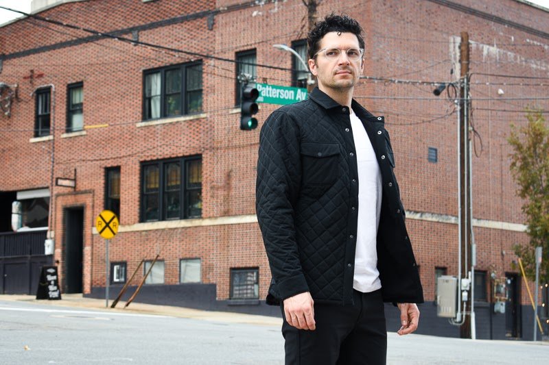 model wearing quilted jacket against brick building