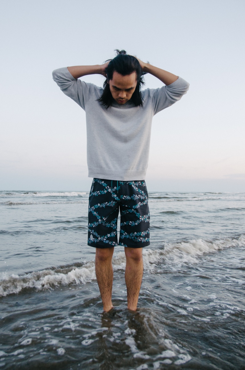Model Wearing Stio CFS Board Short While Holding Hands on Head In The Water At The Beach