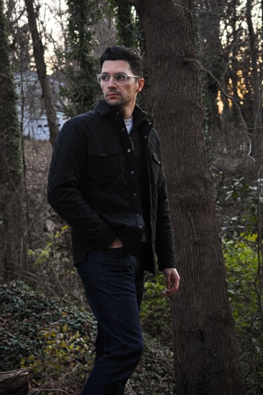 model wearing sweater quilted jacket and dark blue jeans