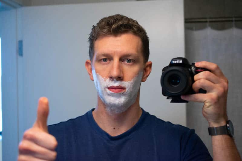 model with shaving cream on face giving thumbs up