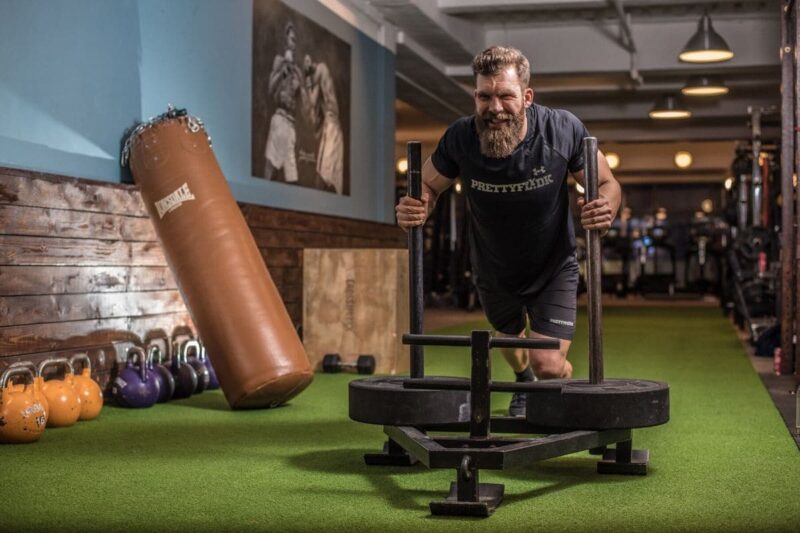 muscle recovery after workout man pushing weighted sled