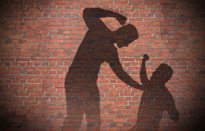 Shadow on a brick wall of a Man beating up another man