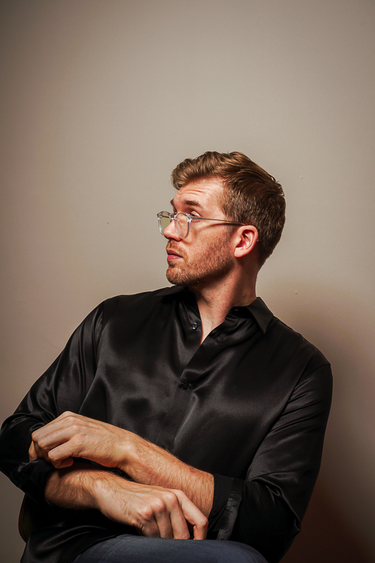 Sitting man wearing black Lilysilk shirt with sleeves rolled