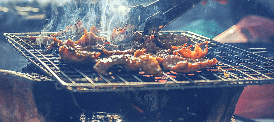 Tongs on barbecue cooking meat