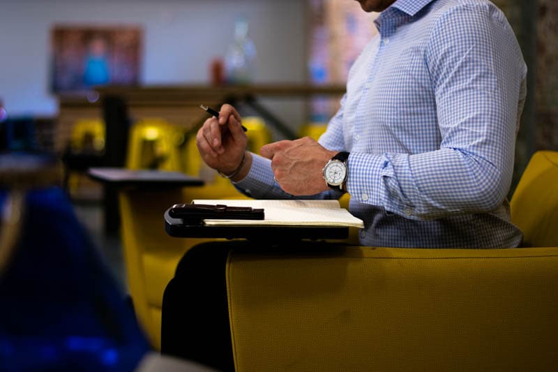 truwear blue checked shirt model in yellow chair with pen performance shirt